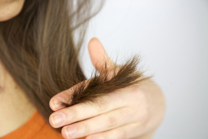 Девушка держит между пальцев волосы