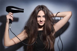 Девушка сушит волосы феном